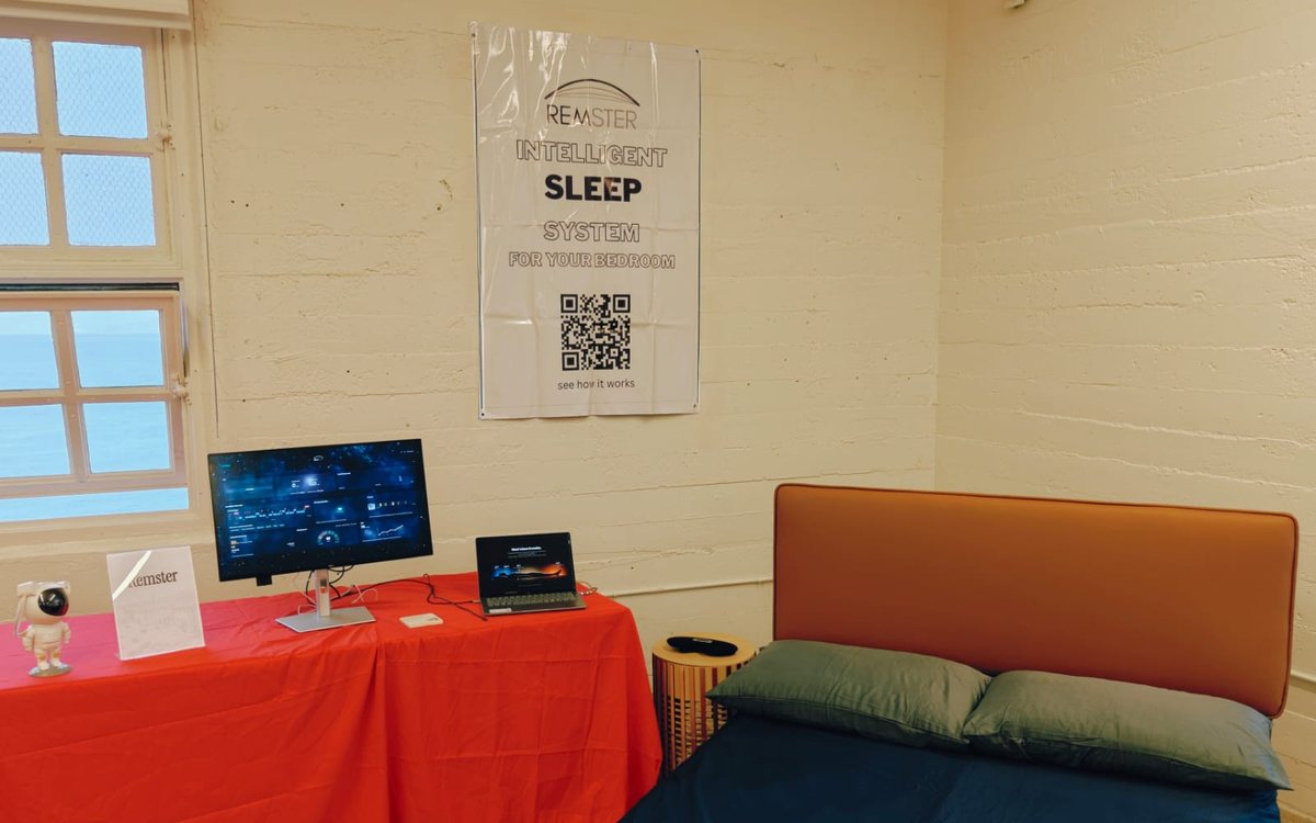 The Remster demo corner: the sleep dashboard on a monitor, a bed with a sleep mask on the nightstand and the Remster poster on the wall