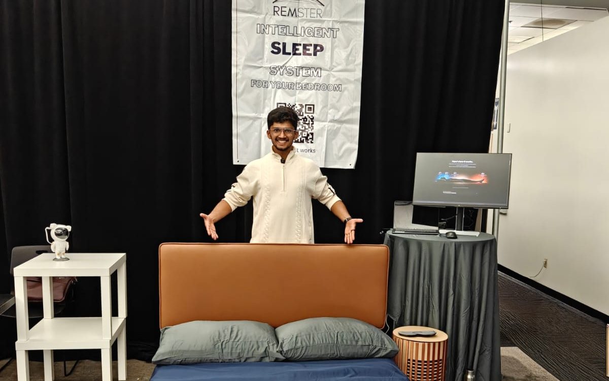 A team member shows the Remster demo bed in front of the Remster poster and the sleep dashboard