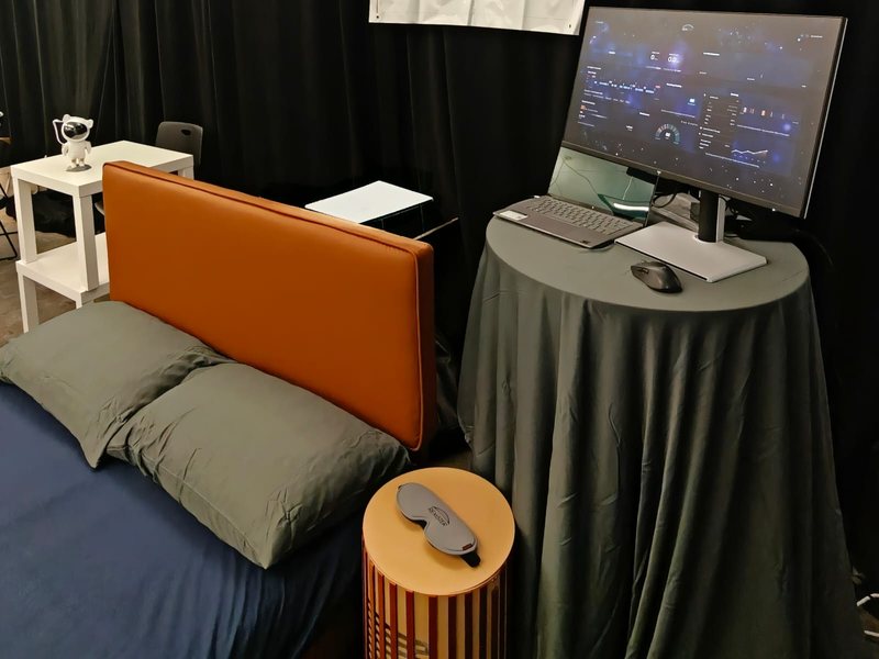 The Remster demo bed with a Remster sleep mask on the nightstand and the sleep dashboard on a monitor beside it